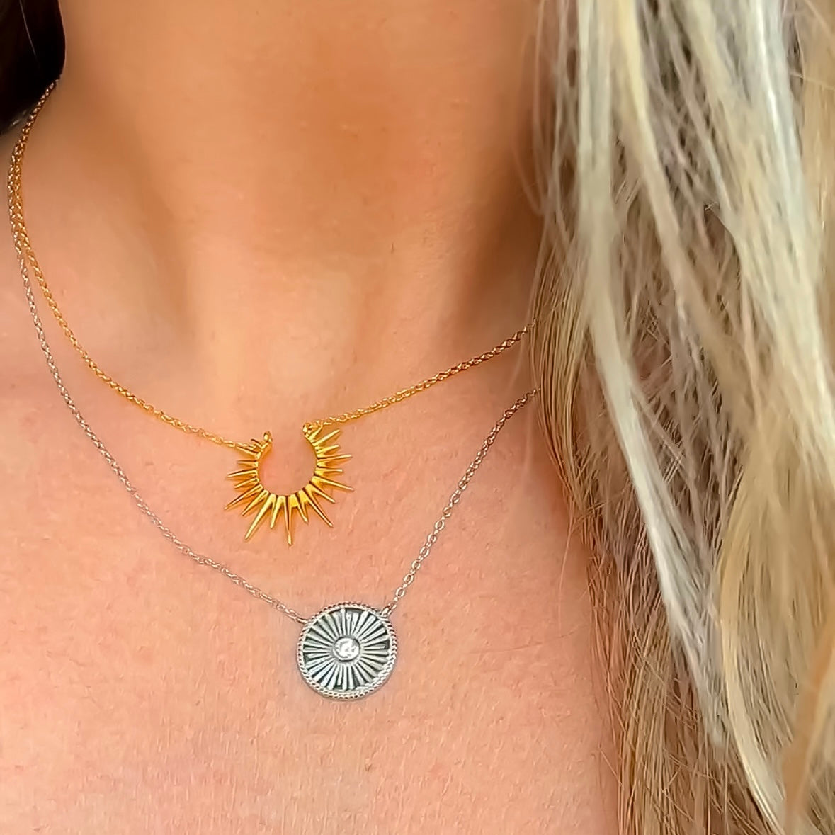 Gold sunburst open sun necklace layered with sterling silver starburst coin necklace from Featherly jewelry