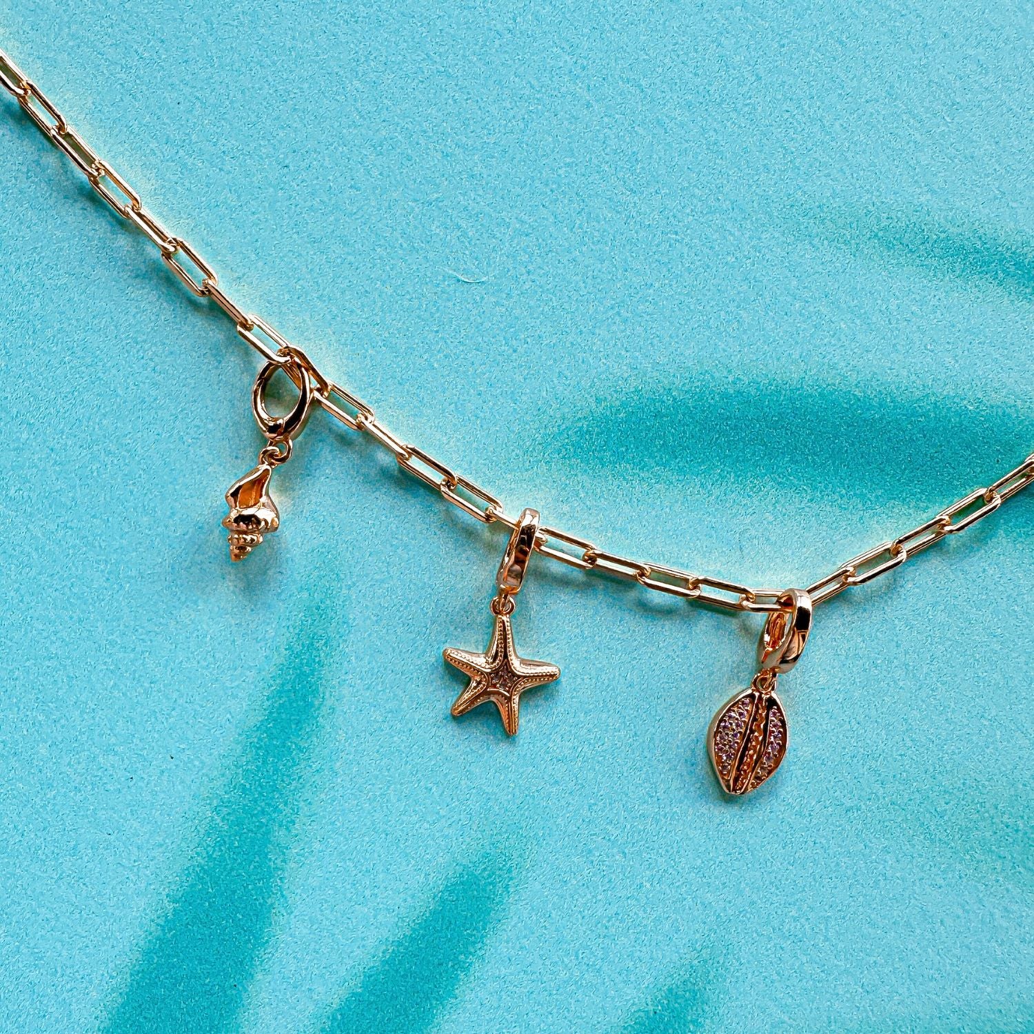 gold seashell, starfish, and cowrie charm necklace on paperclip chain