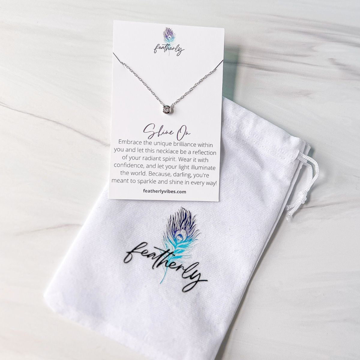 A CZ bezel sterling silver silver necklace on the shine on  meaning card with the Featherly white velvet pouch