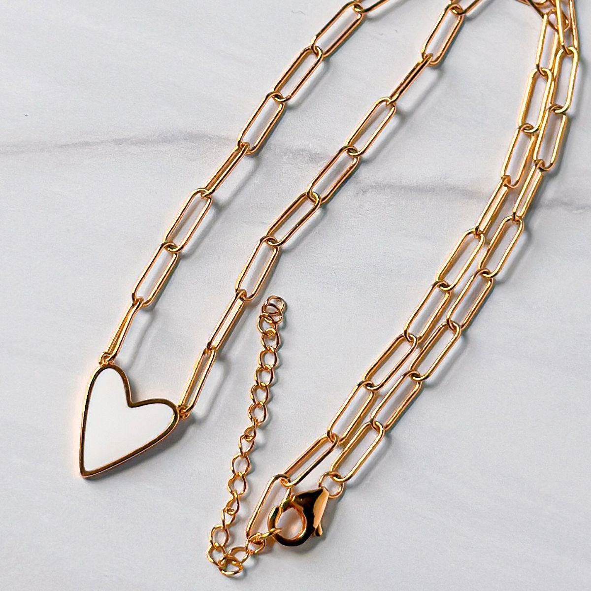 Featherly white enamel heart paperclip chain necklace in gold showing the 2 inch extender