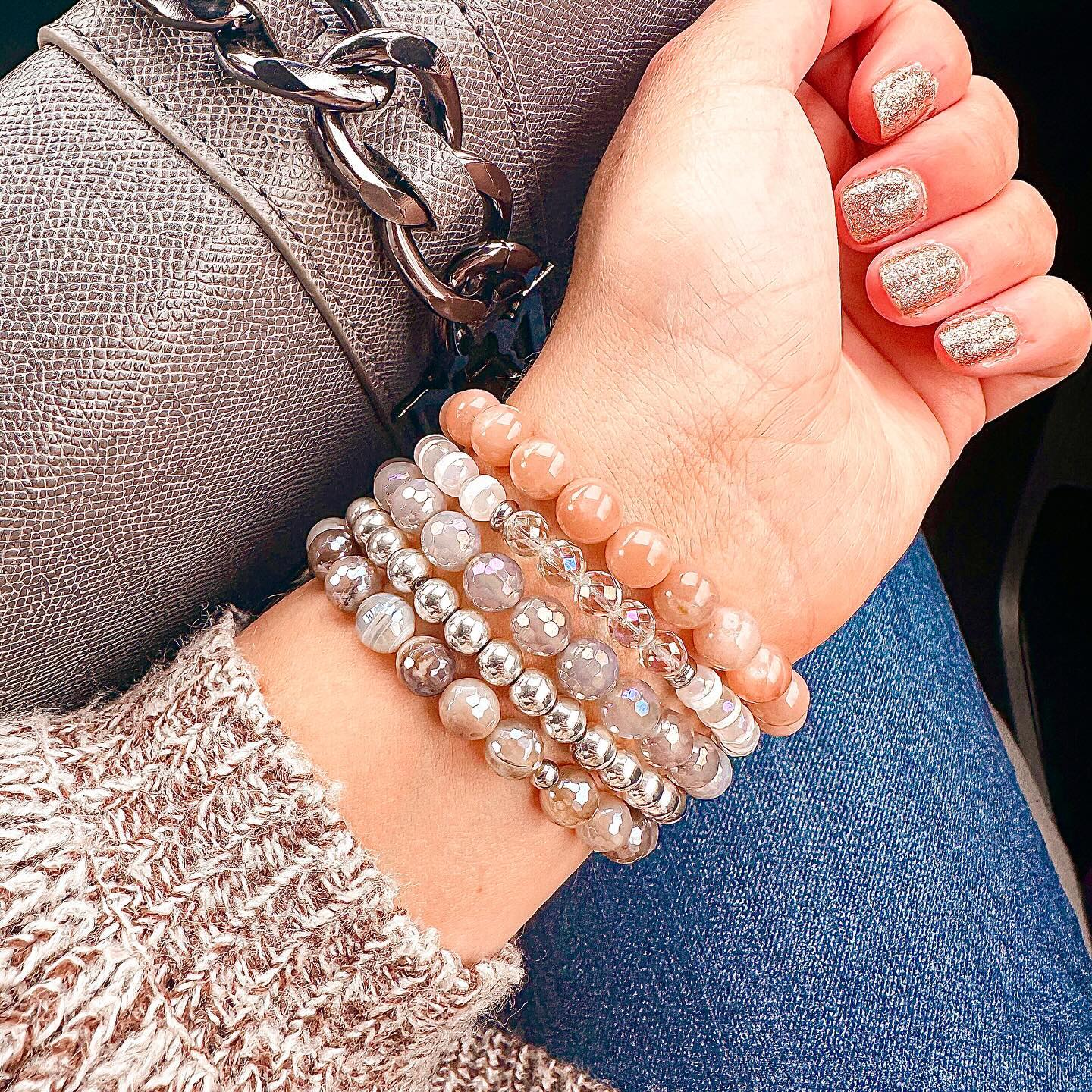 A woman wearing a stack of Featherly beaded stretch gemstone bracelets