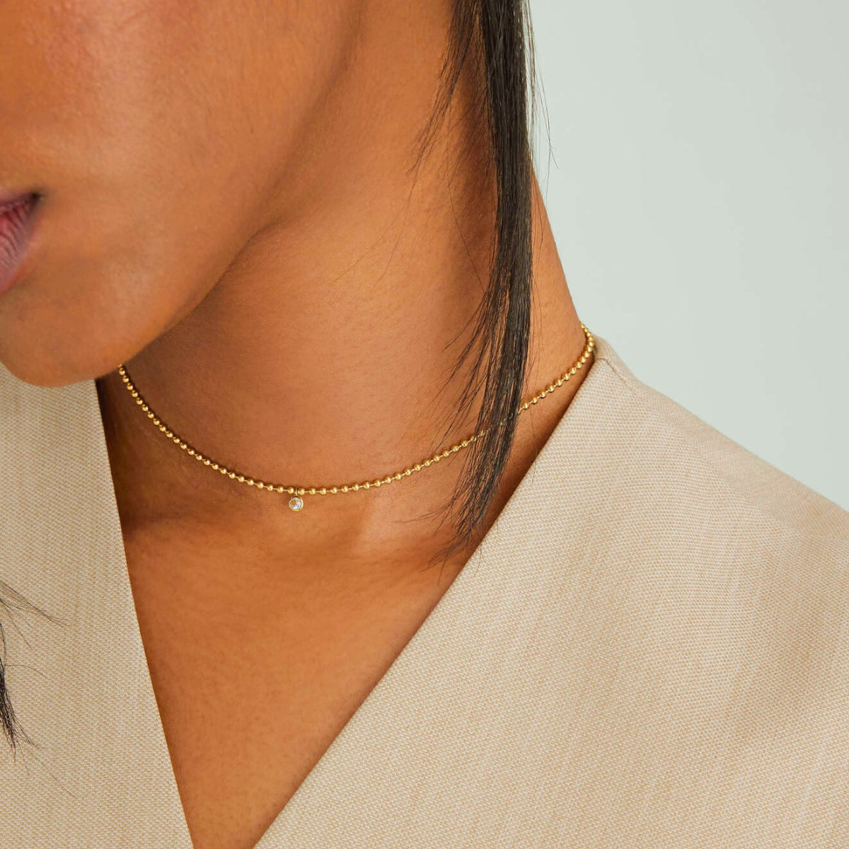 Model wearing the Featherly adjustable cubic zirconia bezel beaded choker necklace in gold